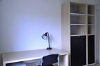 Apartment room with a desk and a bookshelf. Photo. 